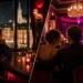 Elegant Vienna bar interior at night with a single guest at the counter and a group at a table further back